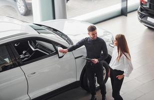 mujer eligiendo coche con la ayuda de un asistente masculino en el interior del salón foto