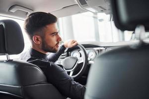 Man in elegant clothes sitting in brand new expencive automobile photo