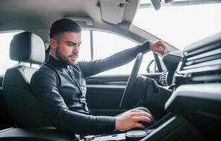 hombre vestido con ropa elegante sentado en un automóvil nuevo y caro foto