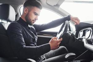 Man in elegant clothes sitting in brand new expencive automobile photo