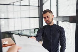 trabajador de oficina en ropa formal de pie en el interior durante el día foto