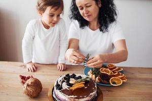 Senior woman with her granddaughter preparing dietical cake on kitchen photo