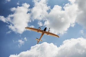 Modern small remote controlled white colored plane flying up in the sky photo