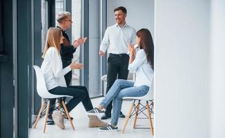 Group of young successful team have work and communicating together indoors in office near windows photo