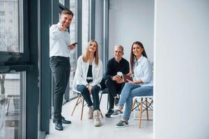 Group of young positive team have work and communicating together indoors in office near windows photo