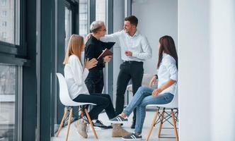 Group of young successful team have work and communicating together indoors in office near windows photo