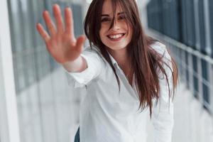 Brunette in white shirt indoors in modern airport or hallway at daytime photo