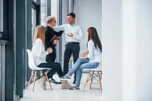 Group of young successful team have work and communicating together indoors in office near windows photo