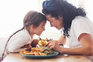 mujer mayor con su nieta comiendo pastel dietético fresco en la cocina foto