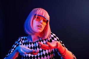 Portrait of young girl with blond hair in eyeglasses in red and blue neon in studio photo