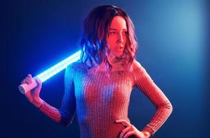 Portrait of young girl with curly hair that holds lighting sticks in red and blue neon in studio photo