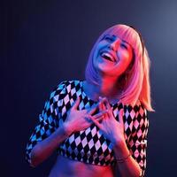 Portrait of young girl with blond hair in red and blue neon in studio photo