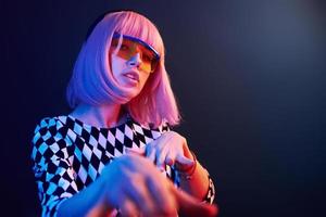 Portrait of young girl with blond hair in eyeglasses in red and blue neon in studio photo