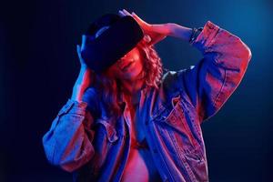 Facial expression of young girl with virtual reality glasses on head in red and blue neon in studio photo