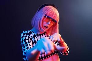 Portrait of young girl with blond hair in eyeglasses in red and blue neon in studio photo