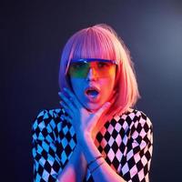 Portrait of young girl with blond hair in eyeglasses in red and blue neon in studio photo