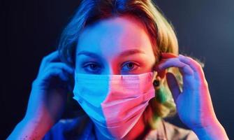 Portrait of girl that wearing protective mask on face in neon lights photo