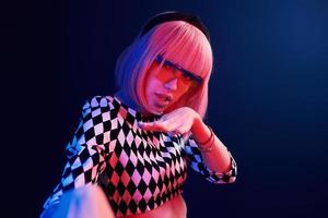 Portrait of young girl with blond hair in eyeglasses in red and blue neon in studio photo