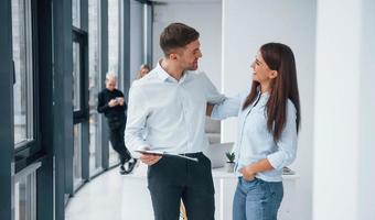 Woman and man talking about documents in front of young successful team that working and communicating together indoors in office photo