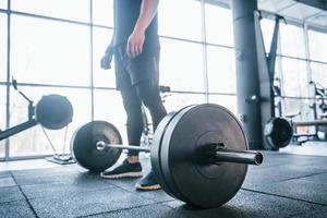 Strong young man in sportive clothes doing exercises with heavy weights in the gym photo