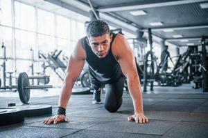 Strong young man in sportive clothes doing push ups in gym photo