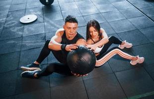 jóvenes deportistas haciendo ejercicios y sosteniendo la pelota juntos en el gimnasio foto