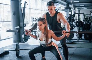 jóvenes deportistas haciendo ejercicios con pesos pesados juntos en el gimnasio foto