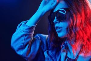 retrato de una joven con gafas de sol en neón rojo y azul en el estudio foto