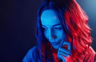 Portrait of young girl with curly hair in red and blue neon in studio photo