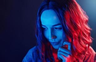 retrato de una joven con el pelo rizado en neón rojo y azul en el estudio foto