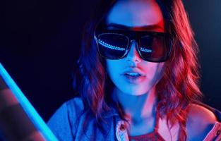 Portrait of young girl in sunglasses in red and blue neon in studio photo