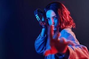 Portrait of young girl that listening to music in headphones in red and blue neon in studio photo