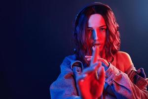 Portrait of young girl that listening to music in headphones in red and blue neon in studio photo