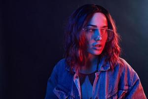 Portrait of young girl in glasses in red and blue neon in studio photo