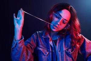 retrato de una joven con gafas con chicle en neón rojo y azul en el estudio foto