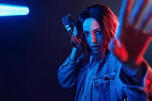 retrato de una joven que escucha música con auriculares en neón rojo y azul en el estudio foto