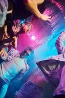 View from below of young people that having fun in night club with colorful laser lights photo