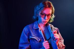 Portrait of young alternative girl in glasses with green hair in red and blue neon light in studio photo