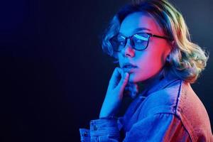 Portrait of young alternative girl in glasses with green hair in red and blue neon light in studio photo