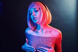 Portrait of young girl with blond hair in red and blue neon in studio photo