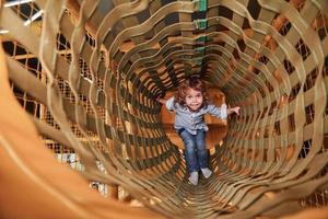 Child have fun in playroom by going through the wooden cage photo