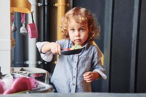 Child in casual clothes have fun by learning how to prepare food photo