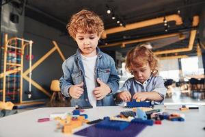 los amiguitos se divierten con los juguetes de construcción en la sala de juegos. juegos educativos de jardín de infantes foto