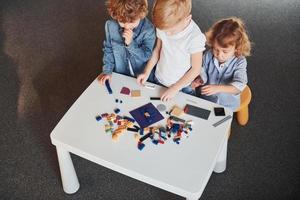 Little friends have fun with construction toys in playroom. Kindergarten educational games photo