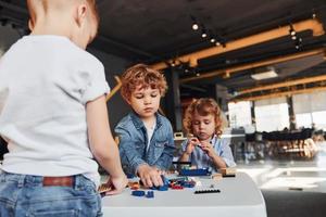 Little friends have fun with construction toys in playroom. Kindergarten educational games photo