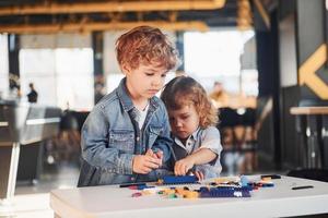 Little friends have fun with construction toys in playroom. Kindergarten educational games photo