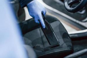 Male worker in uniform cleaning new modern car. Conception of service photo