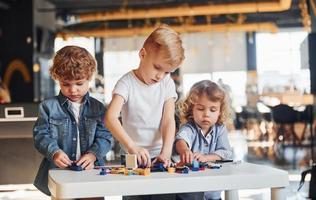 Little friends have fun with construction toys in playroom. Kindergarten educational games photo