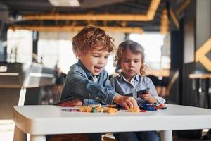 los amiguitos se divierten con los juguetes de construcción en la sala de juegos. juegos educativos de jardín de infantes foto