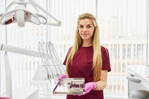 Young female dentist in uniform standing in stomatology office with tools in hands photo